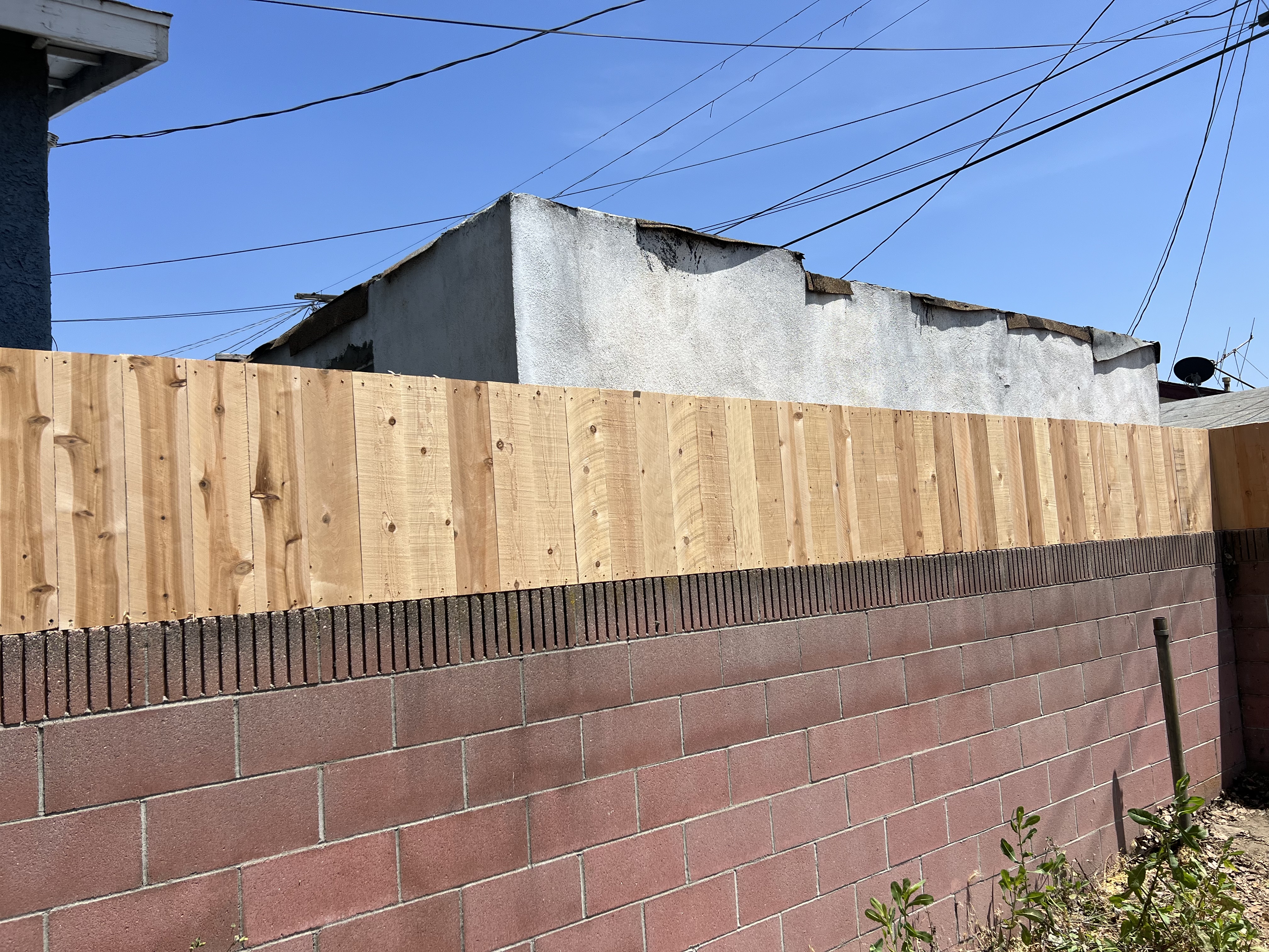 Natural cedar board fence on block wall — close-up detail of boards and block base