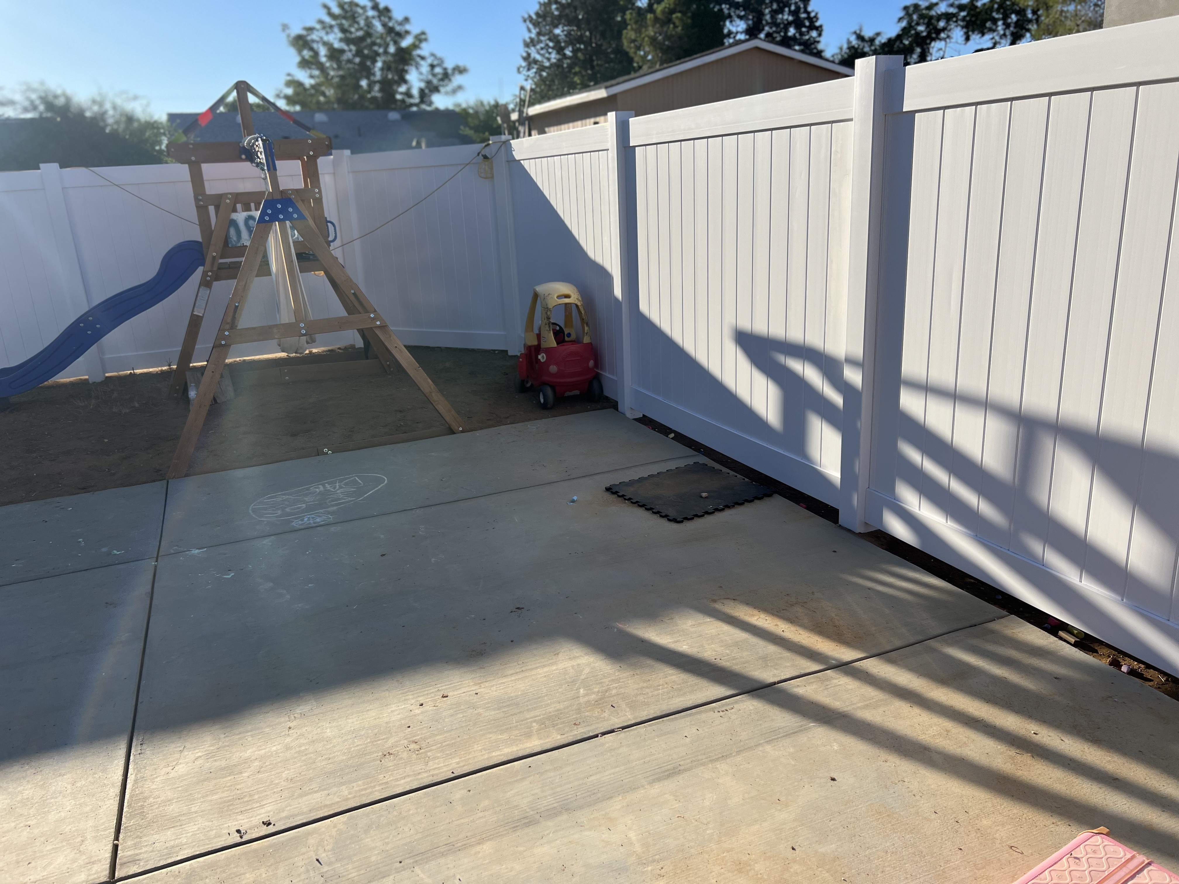 White vinyl full-privacy fence enclosing residential backyard with playground