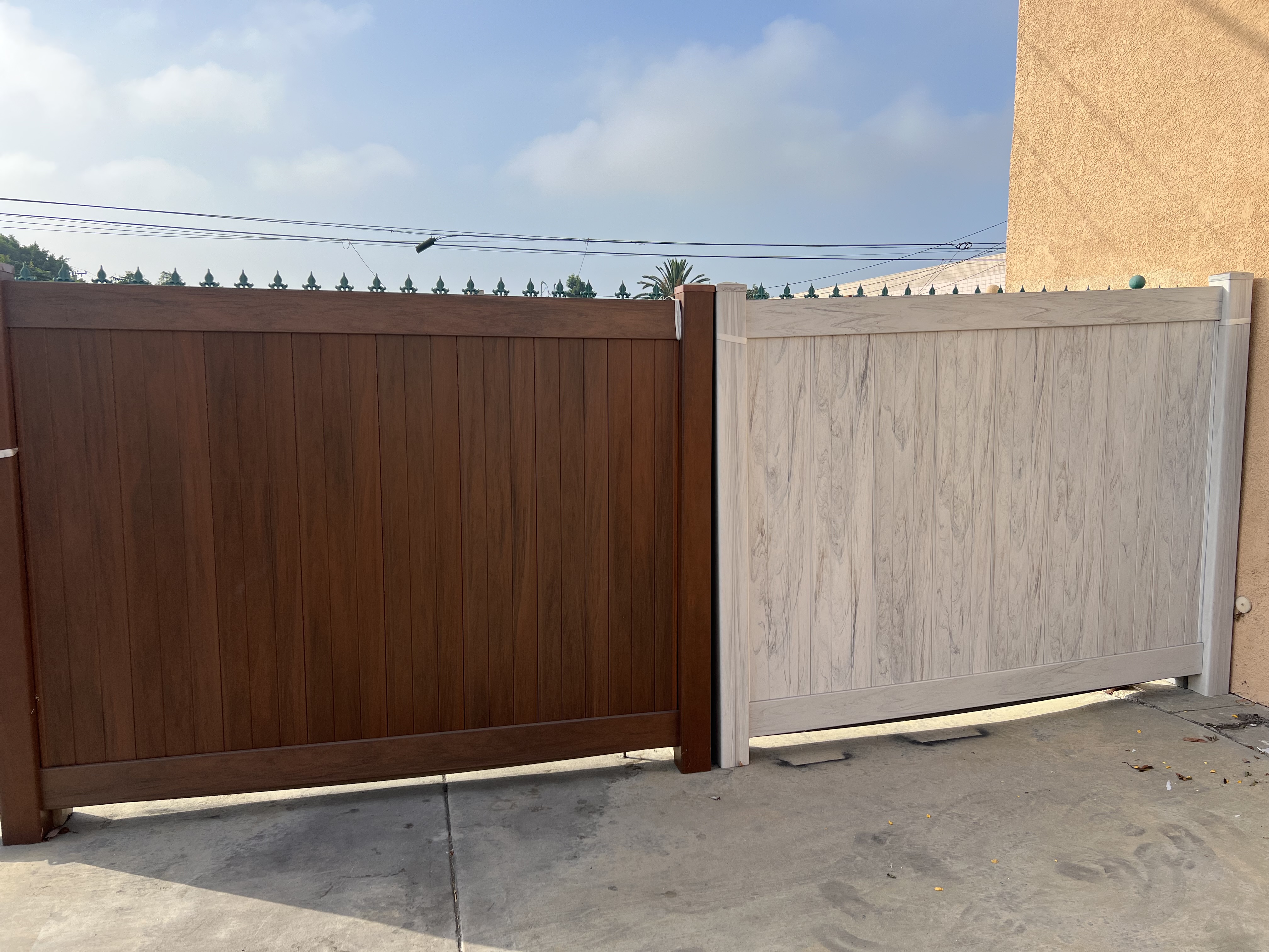 Two composite privacy gates side by side — dark walnut and light gray wood-grain finish